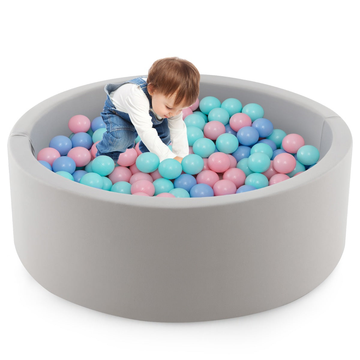 A toddler playing with the colourful balls inside the soft play set