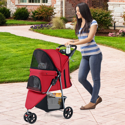 A woman pushing the red pet stroller with a cat inside on a paved path outside a house