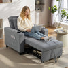 Woman using a laptop on a gray recliner chair in a bright living room.