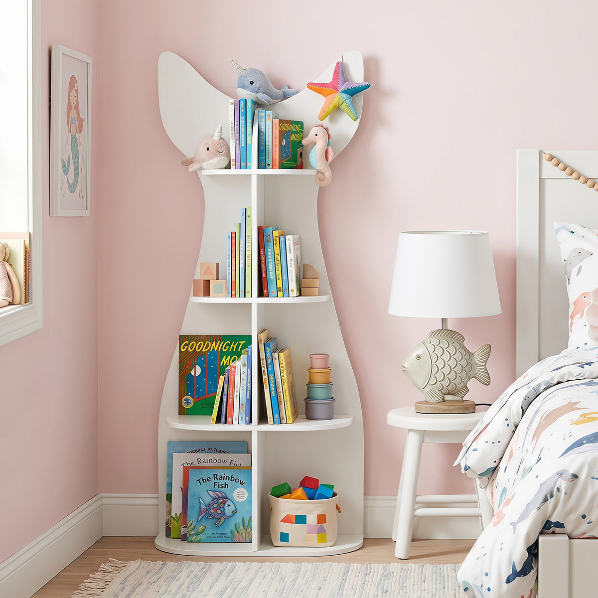 The white fish-shaped kids bookshelf with open shelves filled with books and toys