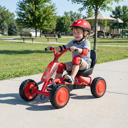 Child riding the red pedal go kart in a park on a sunny day