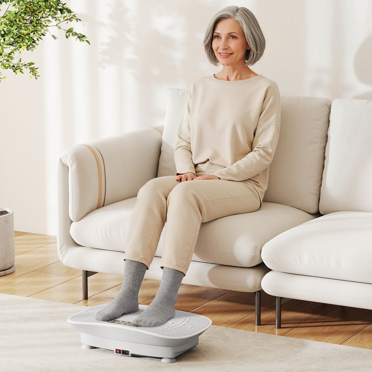 Woman sitting on a sofa using the grey exercise machine