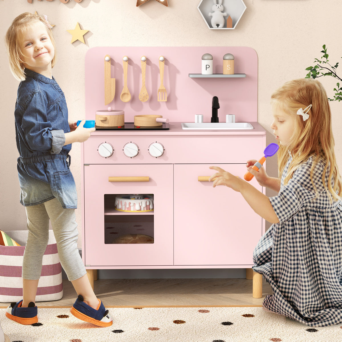 Two young children playing with the pink play kitchen set in a decorated nursery room