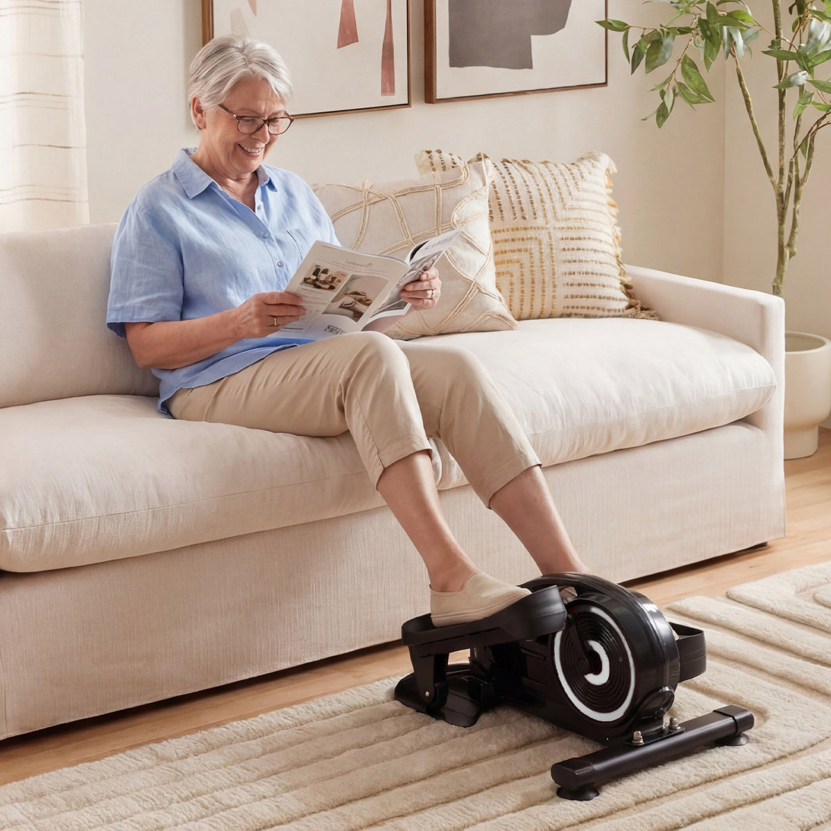 An older woman using the under desk elliptical pedal exerciser while relaxing on a sofa