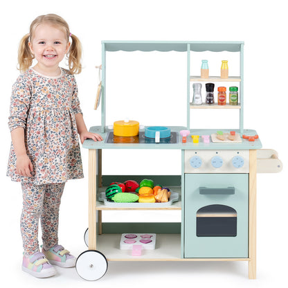 A young girl standing next to the wooden play kitchen set