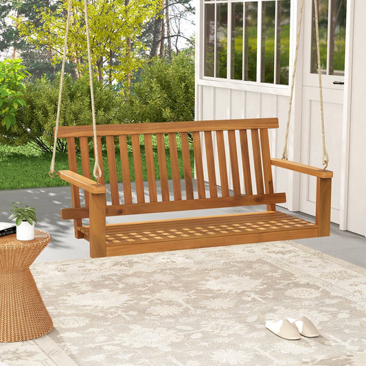 The wooden porch swing with slatted seat and backrest on a patio with a rug