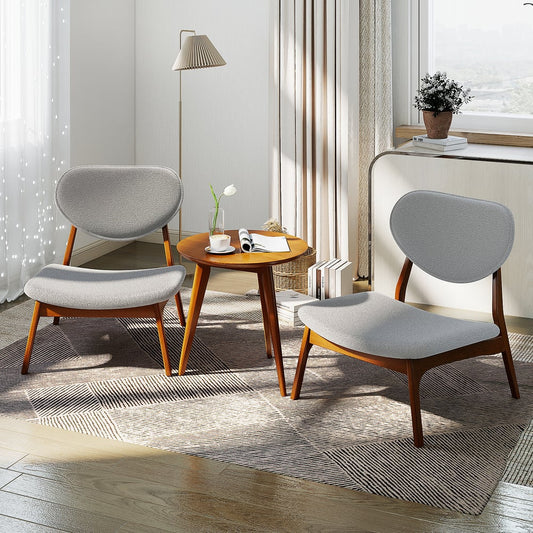 Two grey accent chairs and a side table arranged in a cosy living room setting with a lamp and books