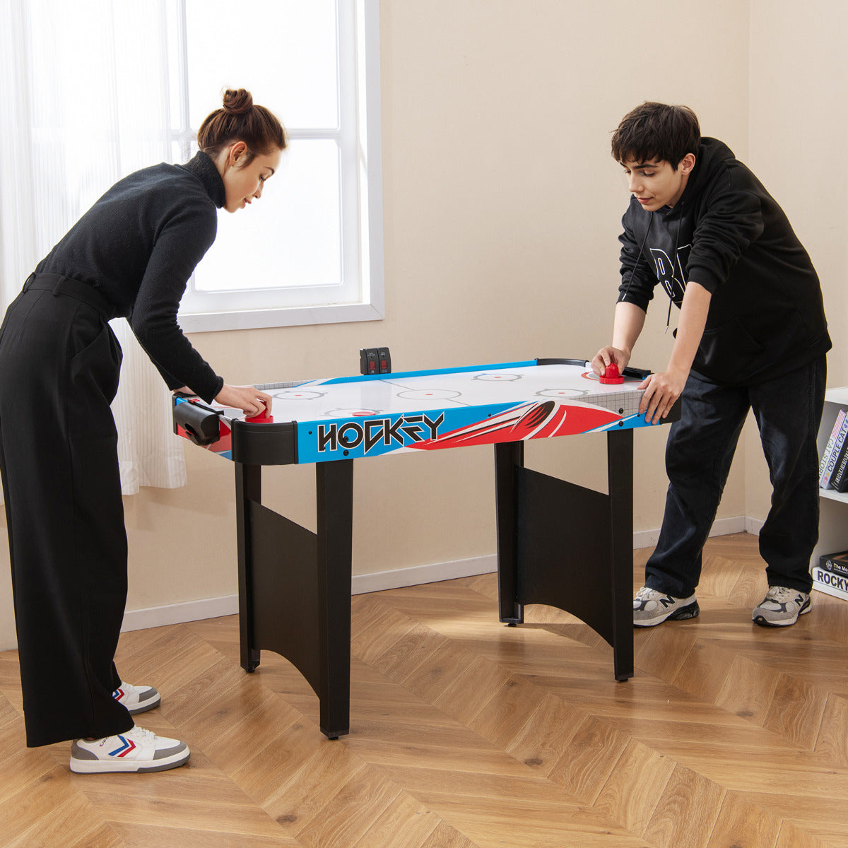 Teenagers playing the game room air hockey table
