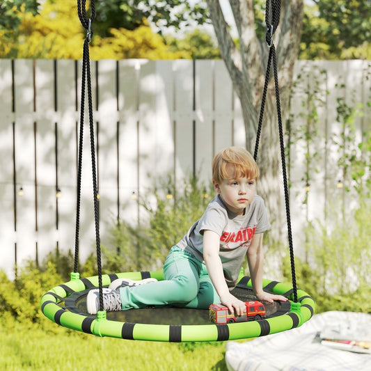 A young boy sits on the round swing seat in a garden setting