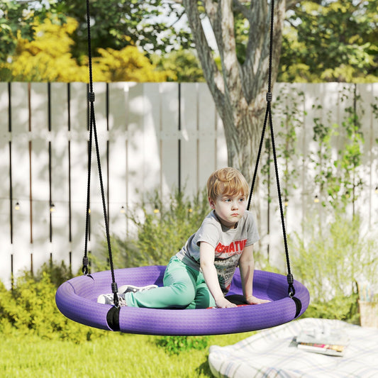 A young boy sits on a purple nest seat swing in a garden setting