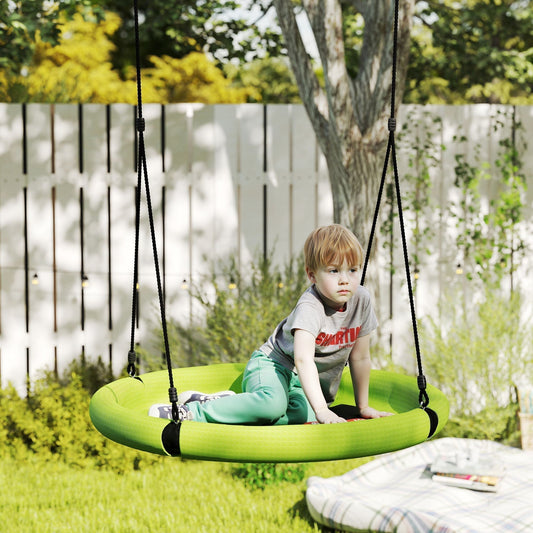 The nest swing hanging from a tree in a sunny garden with a young boy sitting on it