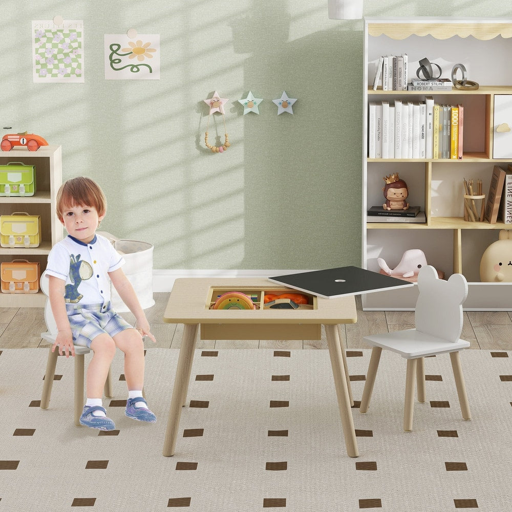 A young boy sits at the kids activity table in a playroom setting with toys and books
