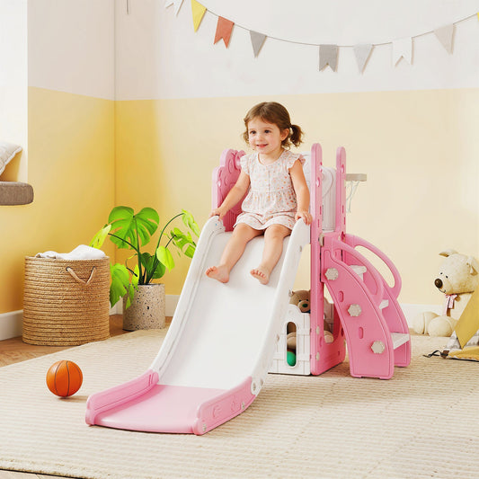A toddler sitting at the top of the pink kids slide set in a bright playroom