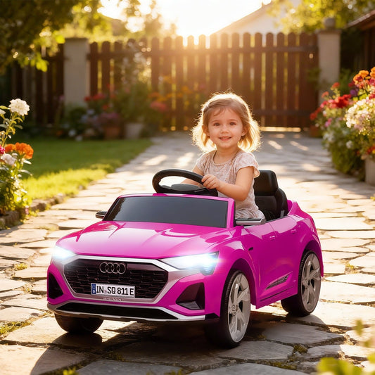 A happy young girl driving the pink ride-on car in a garden setting