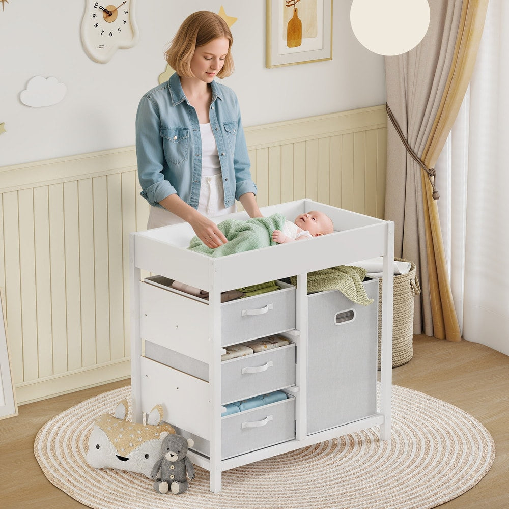 A baby changing unit with drawers and storage cube in a nursery with a mother changing a baby