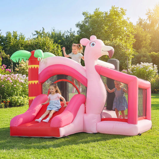 Children playing on the pink inflatable bounce house with slide in a sunny garden