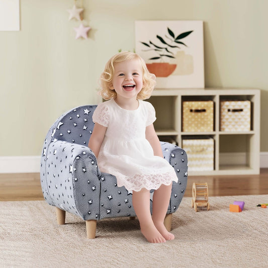A happy young girl sitting on the grey star-patterned kids armchair