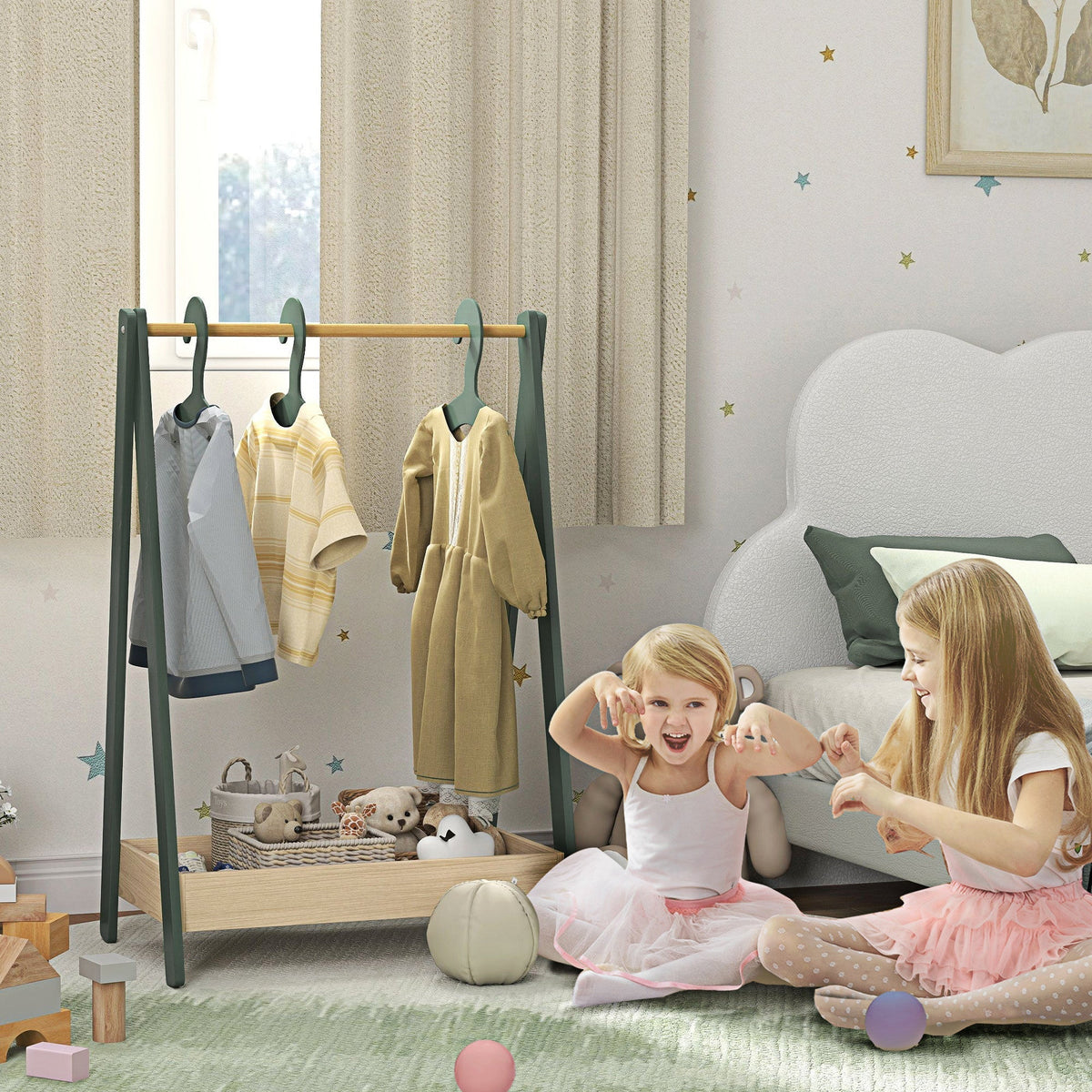 The green kids clothes rail with 3 hangers and bottom storage shelf in a nursery with two young girls playing