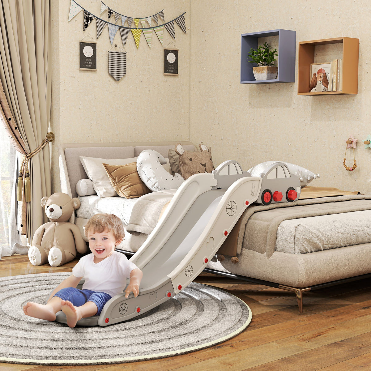 A toddler happily slides down the grey and white kids slide for bed, sofa, in a bedroom setting