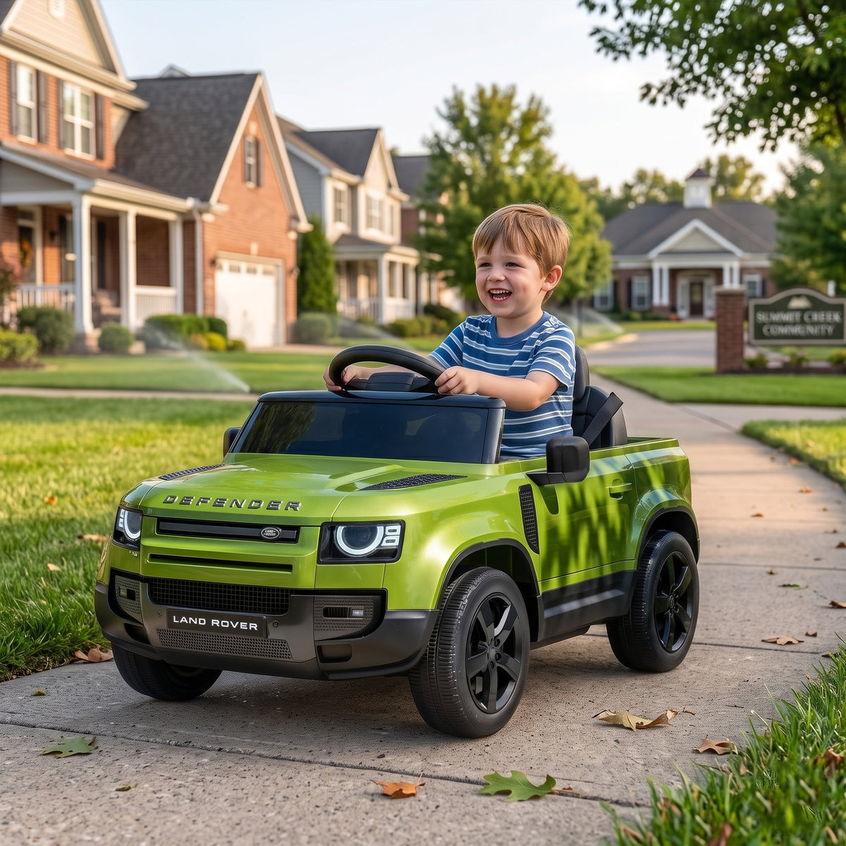 A young boy smiling while sitting in the green ride-on car on a suburban pavement
