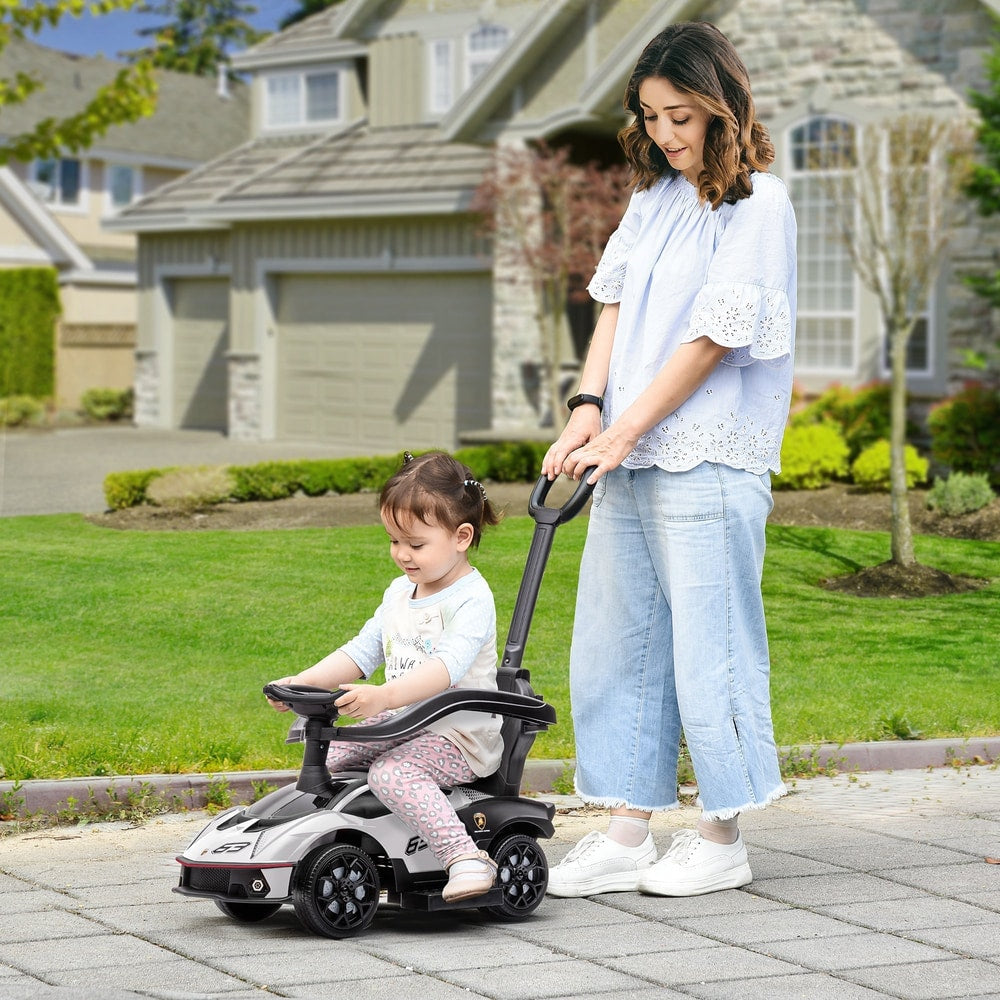 The ride on car being pushed by a woman on a paved driveway with a young child sitting inside