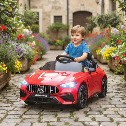 A happy young boy driving the red kids electric car down a cobbled path lined with flowers
