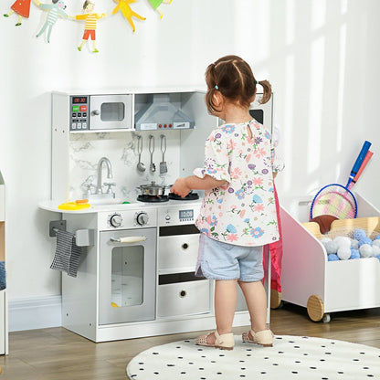 A young child playing with the white and grey role play toy kitchen in a bright room