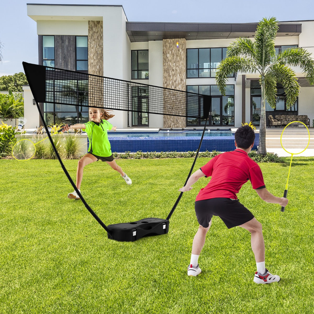 the portable badminton net set standing on a green lawn in front of a modern house