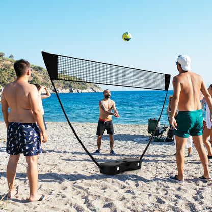 the portable badminton net set positioned on a sandy beach with people playing nearby