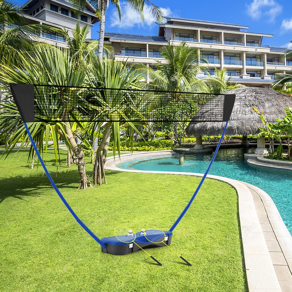 The portable badminton net set on grass next to a swimming pool with two shuttlecocks on the base