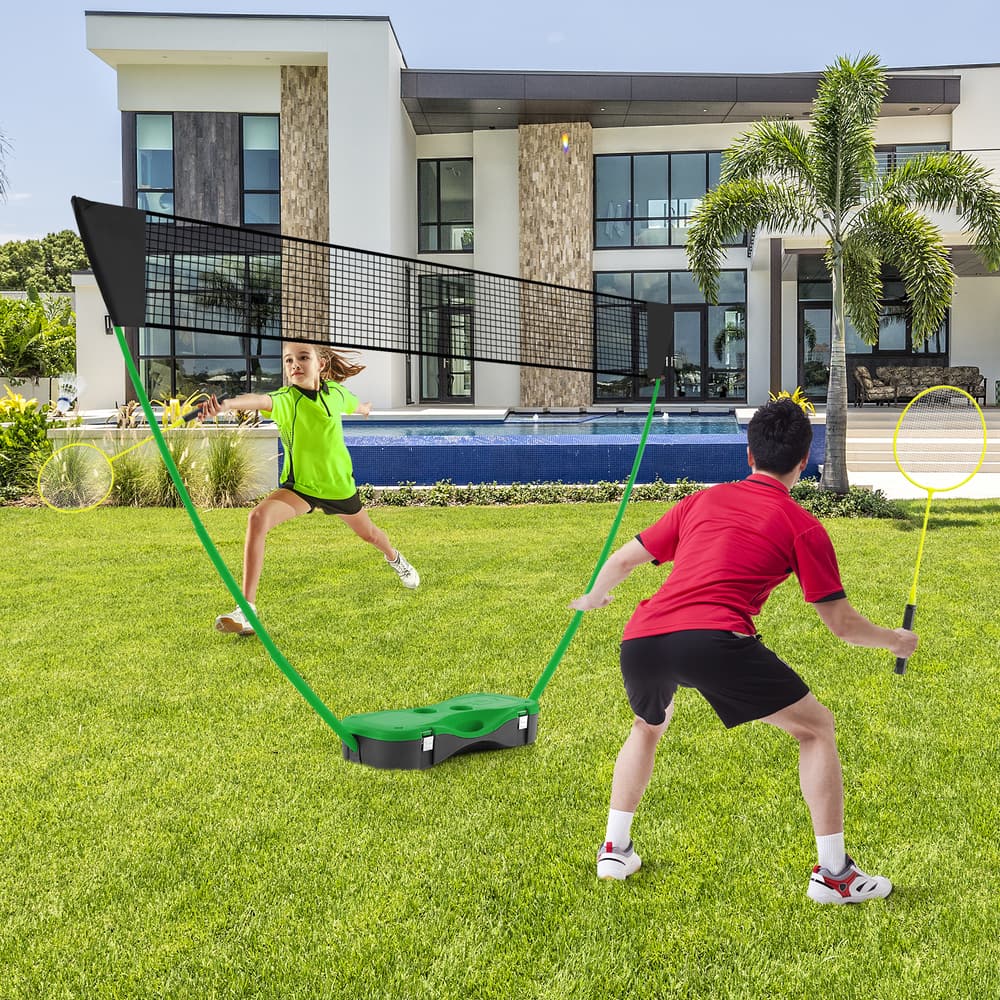 The badminton net set with green base and black net standing on a green lawn