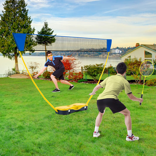 Two men playing badminton with the portable net set in a grassy garden near a lake