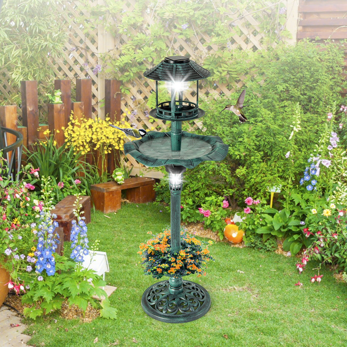 The green bird bath and feeder positioned on a lawn with a wooden fence