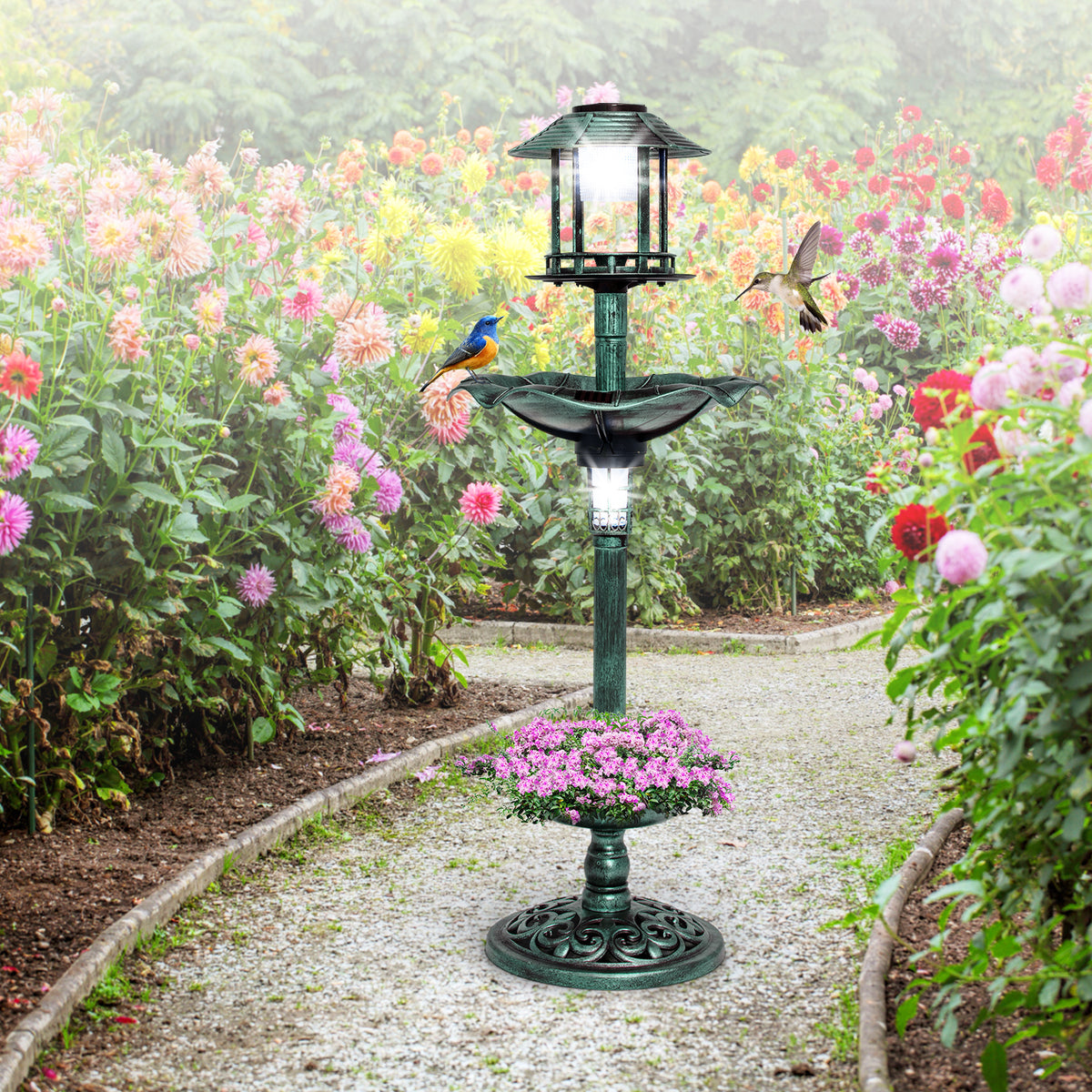 The green bird bath and feeder standing on a gravel path in a garden