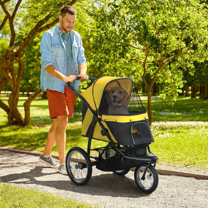 A man pushes a yellow and black three-wheeled dog carrier with a dog inside along a path in a park