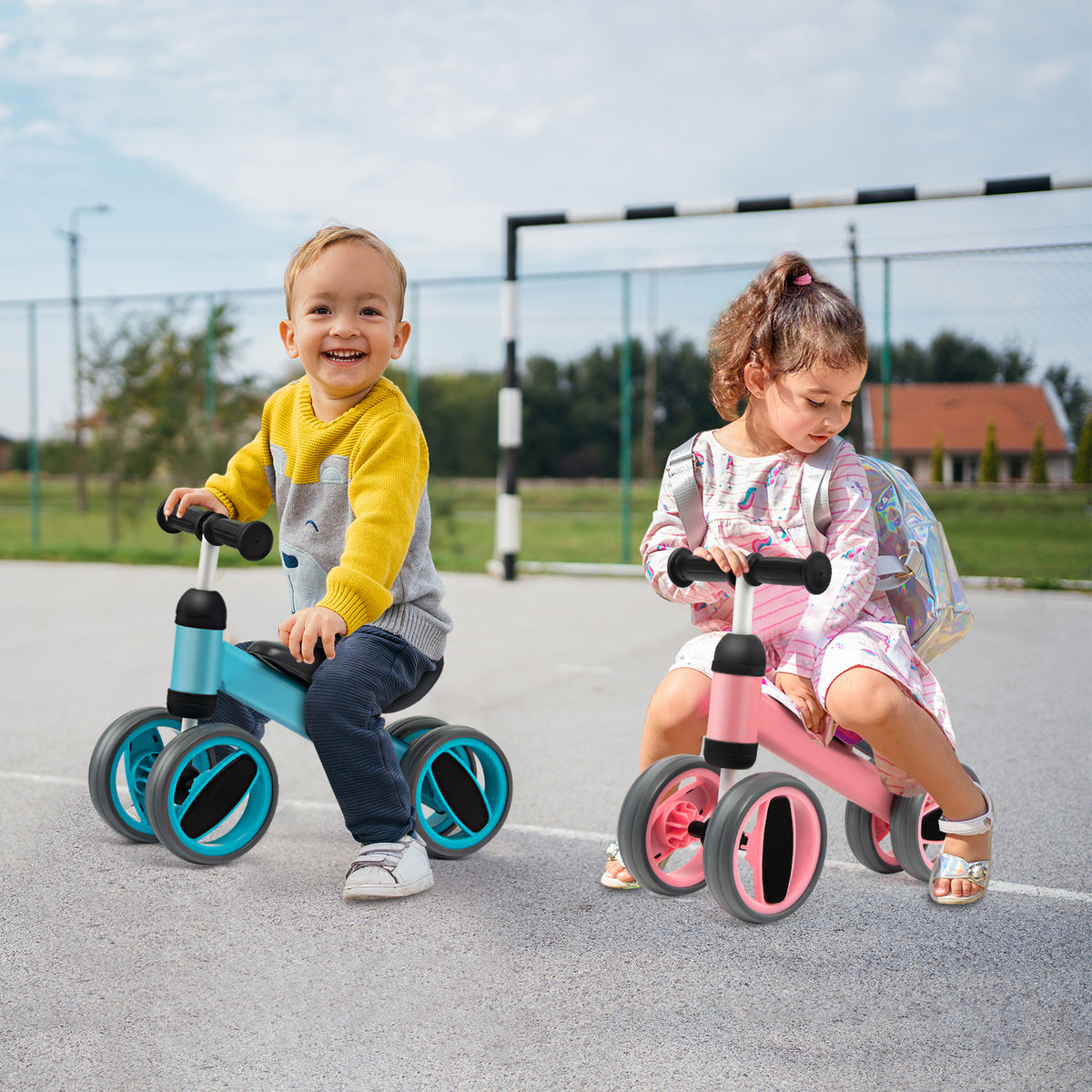 The balance bike being ridden by two children on a paved outdoor playground surface