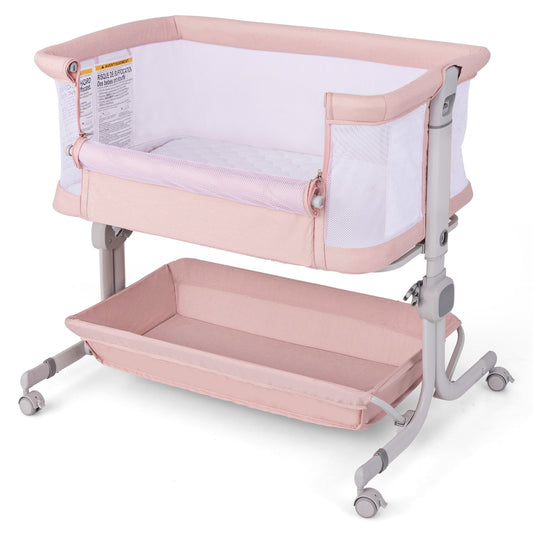 Baby Bassinet Bedside Sleeper in pink with a storage shelf and wheels on a white background