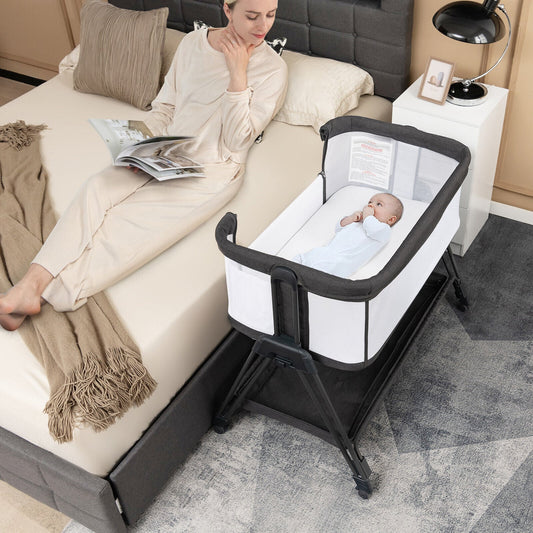 The bedside sleeper positioned next to a large bed with a mother and baby inside