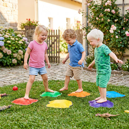 Three children playing on colourful stepping stones in a garden