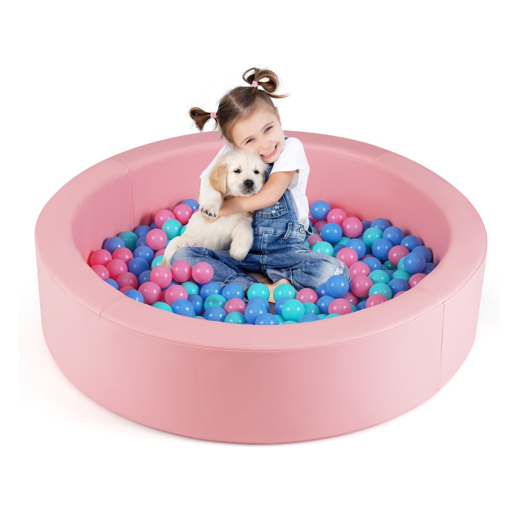 A happy girl hugging a puppy in the pink foam ball pit