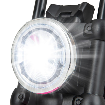 A close-up of the bright circular headlight on the front of the kids electric motorbike