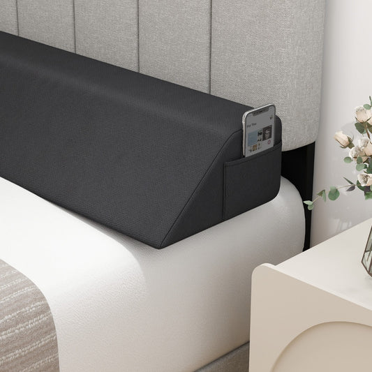 The wedge pillow has a side pocket holding a mobile phone, placed against a headboard