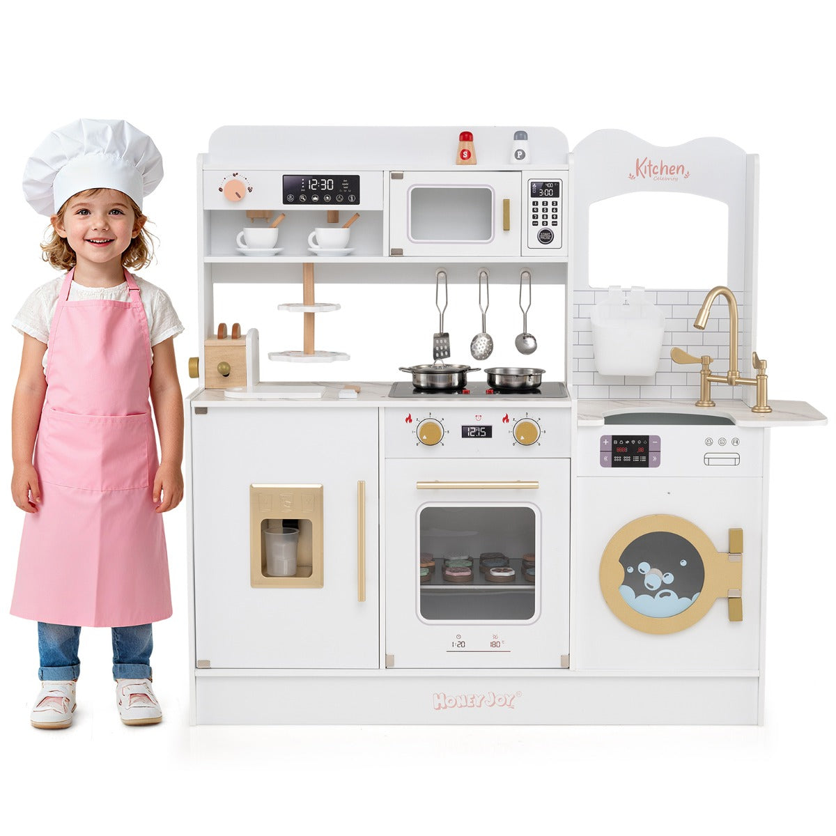 A young girl wearing a chef's hat and apron standing in front of the toy kitchen set
