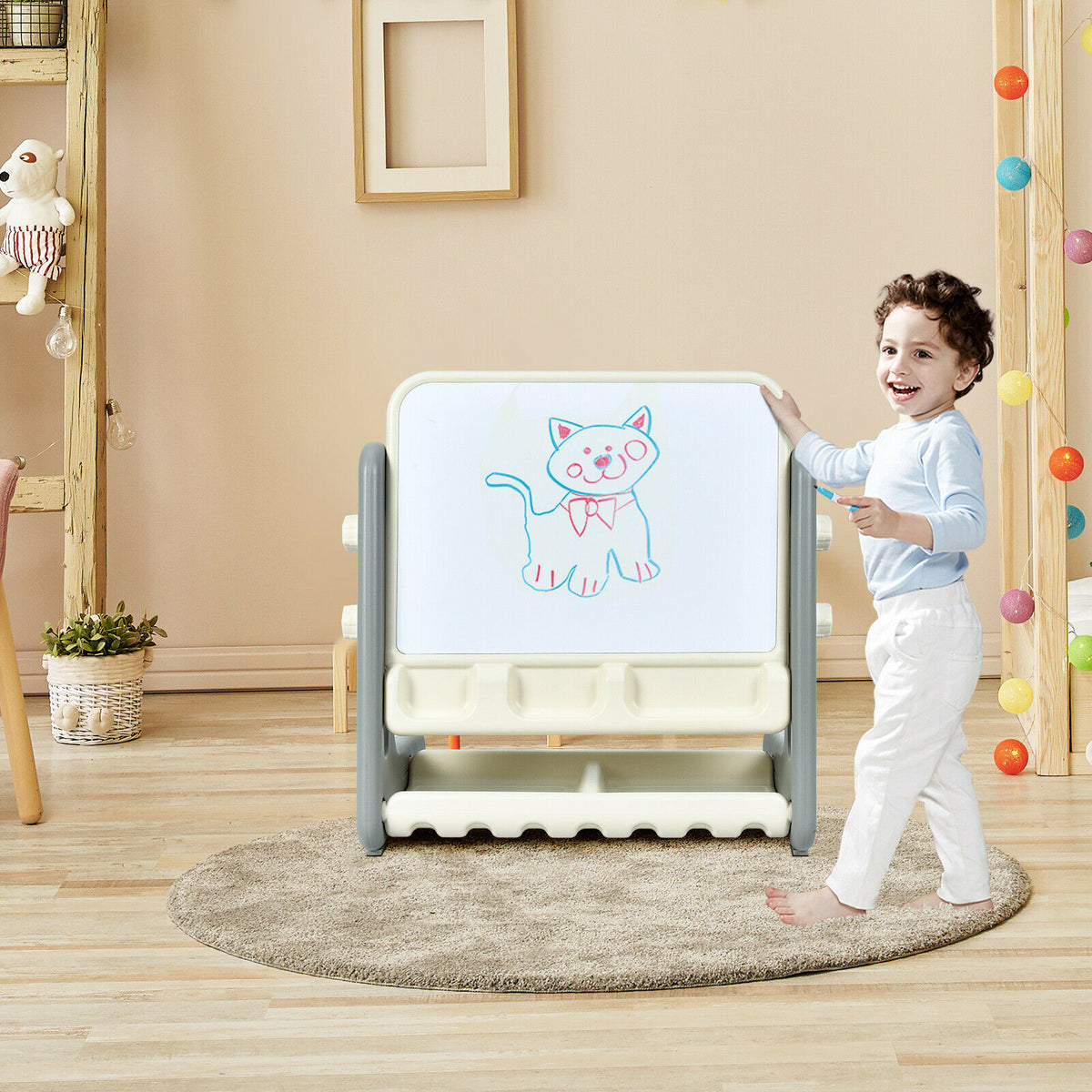 A young boy stands by the art easel table and chair set