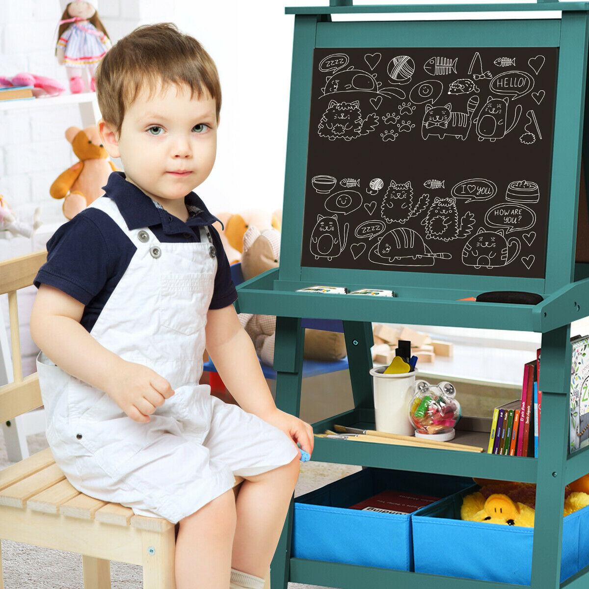 A young boy sitting on a stool next to the blue children's art easel