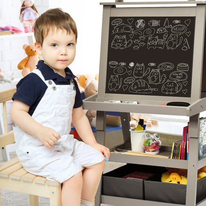 The art easel with a young boy sitting beside it while looking at the blackboard side