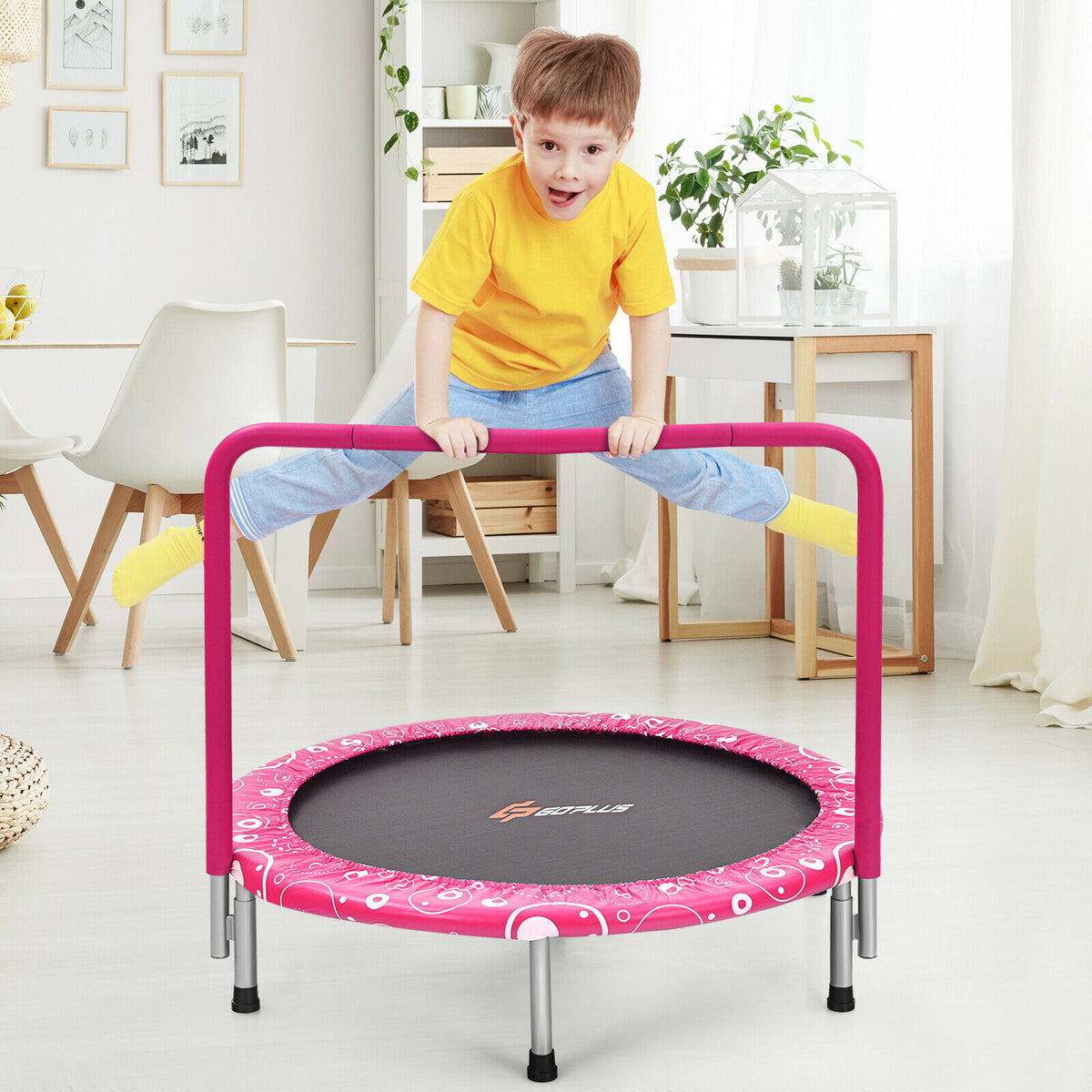 A boy jumps on the pink folding trampoline in a living room