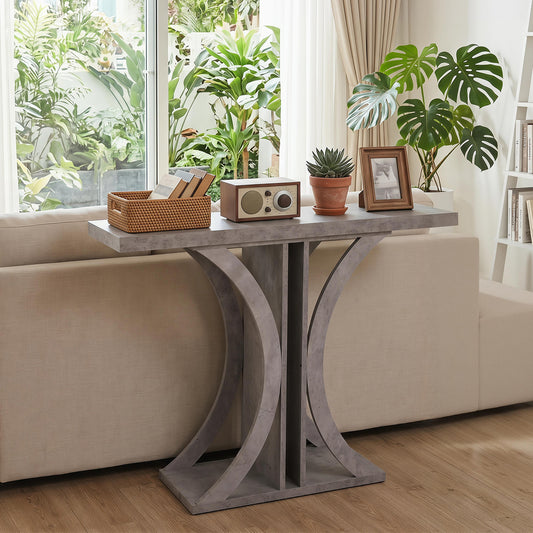 Grey entryway table with a geometric frame, shown in a living room setting with a sofa and plants