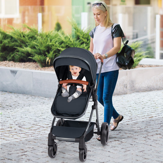 The dark blue baby stroller with a baby inside being pushed by a woman on a pavement