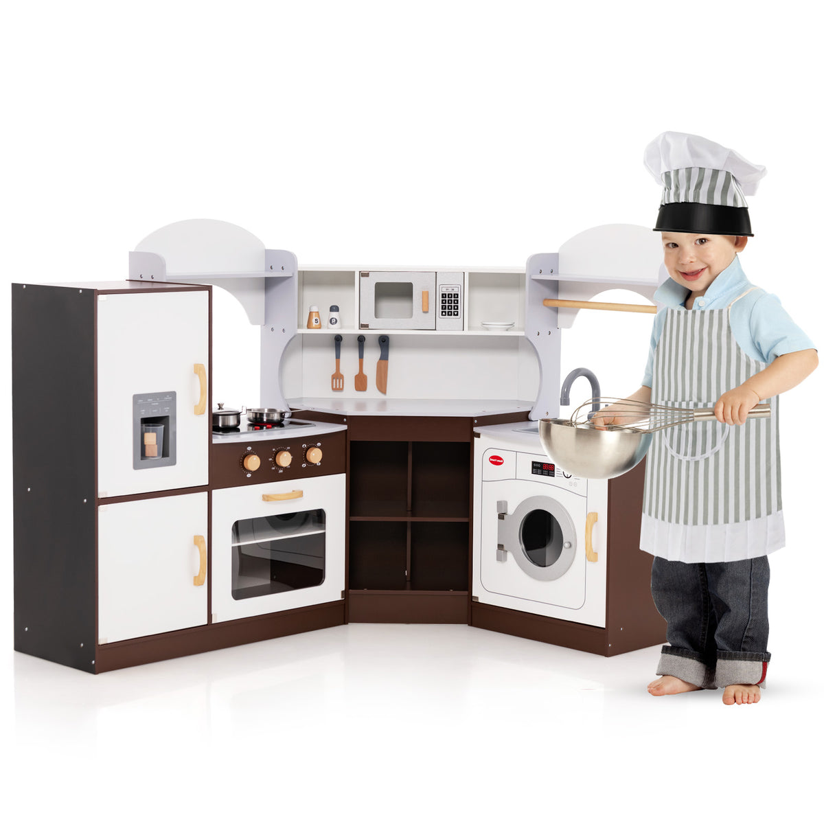 A happy toddler boy with a whisk standing by the play kitchen